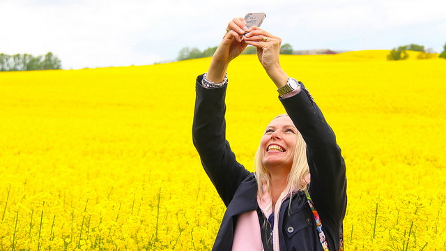 woman takes a selfie in a field of yellow flowers