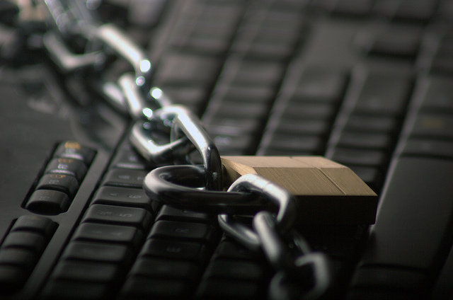 A black computer keyboard with a chain and padlock.