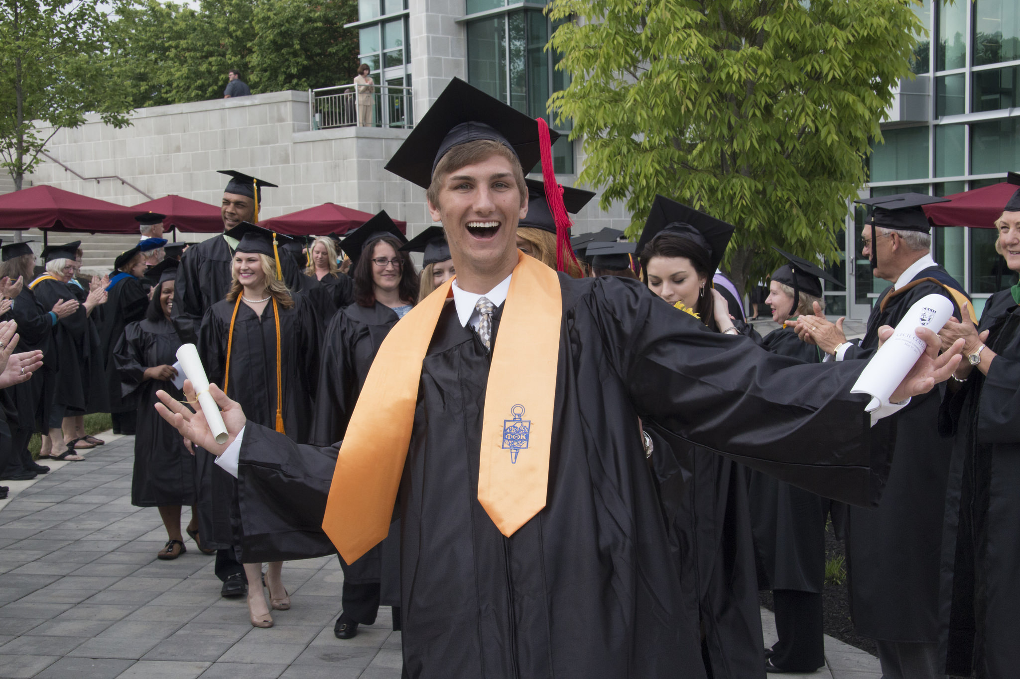 Phi Theta Kappa college graduate celebrates with other students.