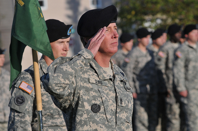Army soldiers in combat uniforms and black berets stand in formation.