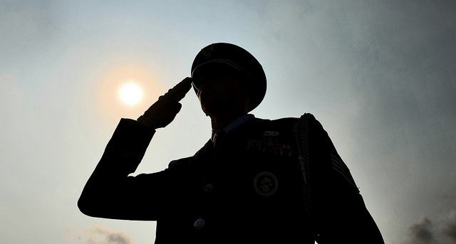 A silhouette of a soldier in dress uniform saluting.