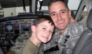 Soldier poses with his son in a cockpit