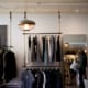 Retail clothing store with racks and lamps hanging by ropes from the ceiling