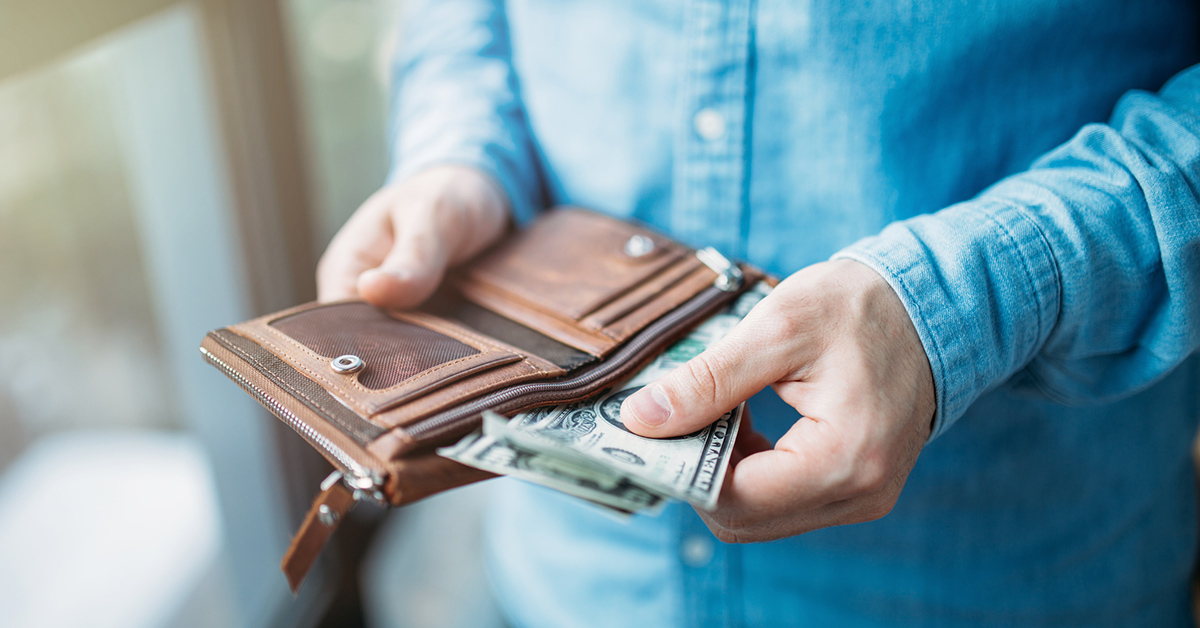 A businessman puts money into the breast pocket of his jacket