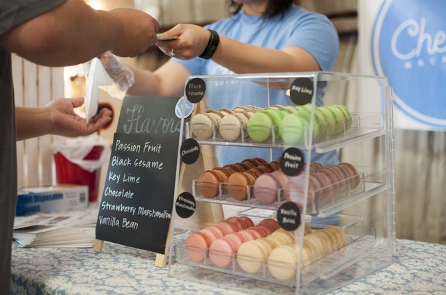 customer makes a purchase from vendor selling multi-colored macaroons