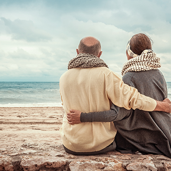 Two seniors on the beach enjoying a vacation they purchased through a gated offer.