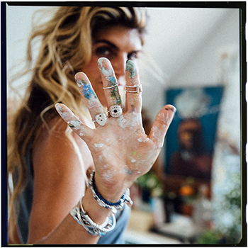A woman's hand featuring rings and bracelets from Alex and Ani. Customers opt-in to a relationship with Alex and Ani through gated offers.
