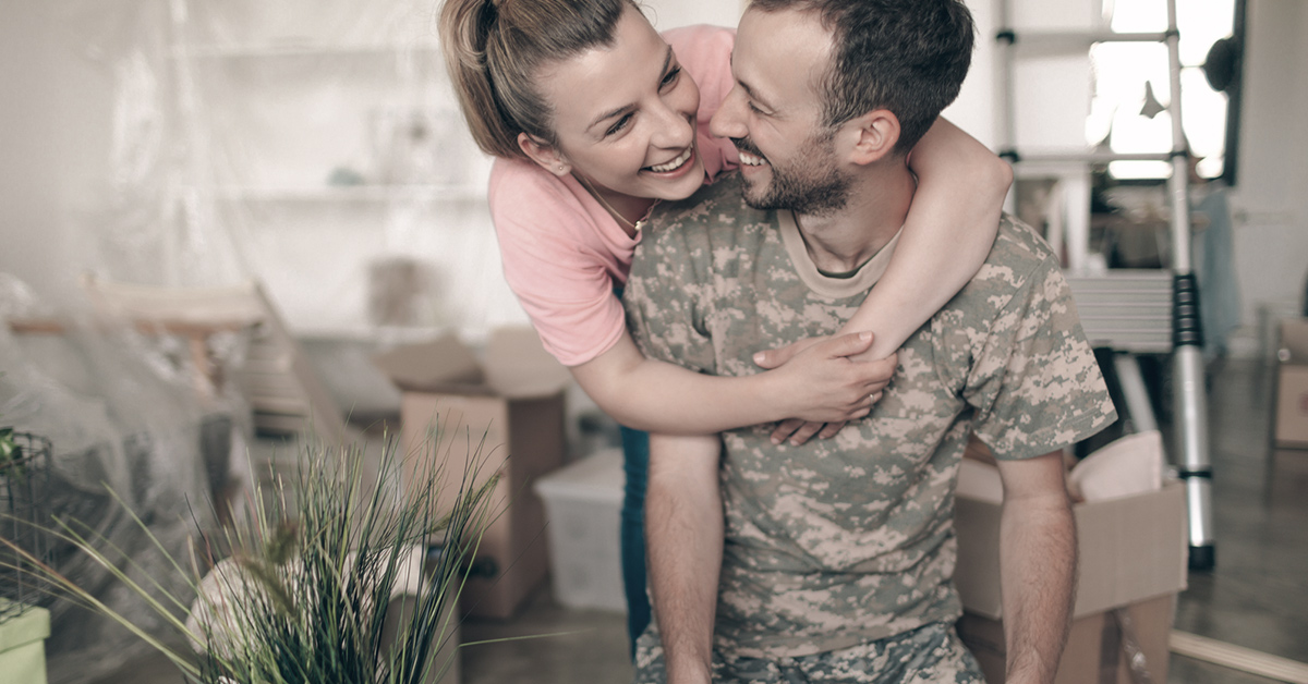 Photo of a young man in a soldier uniform, moving into a new apartment with his wife