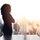 A loan officer contemplating financial services customer acquisition as she looks out a window at a city skyline.