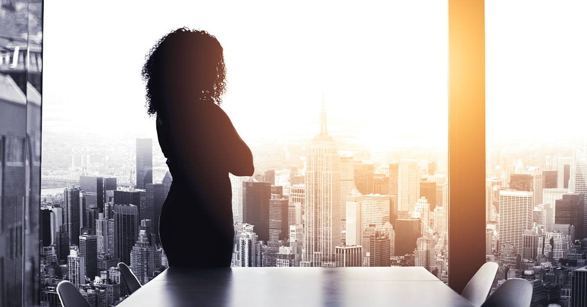 A loan officer contemplating financial services customer acquisition as she looks out a window at a city skyline.