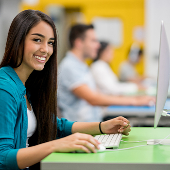 Female student at a desktop computer using free software Alteryx provided to grow customer loyalty.