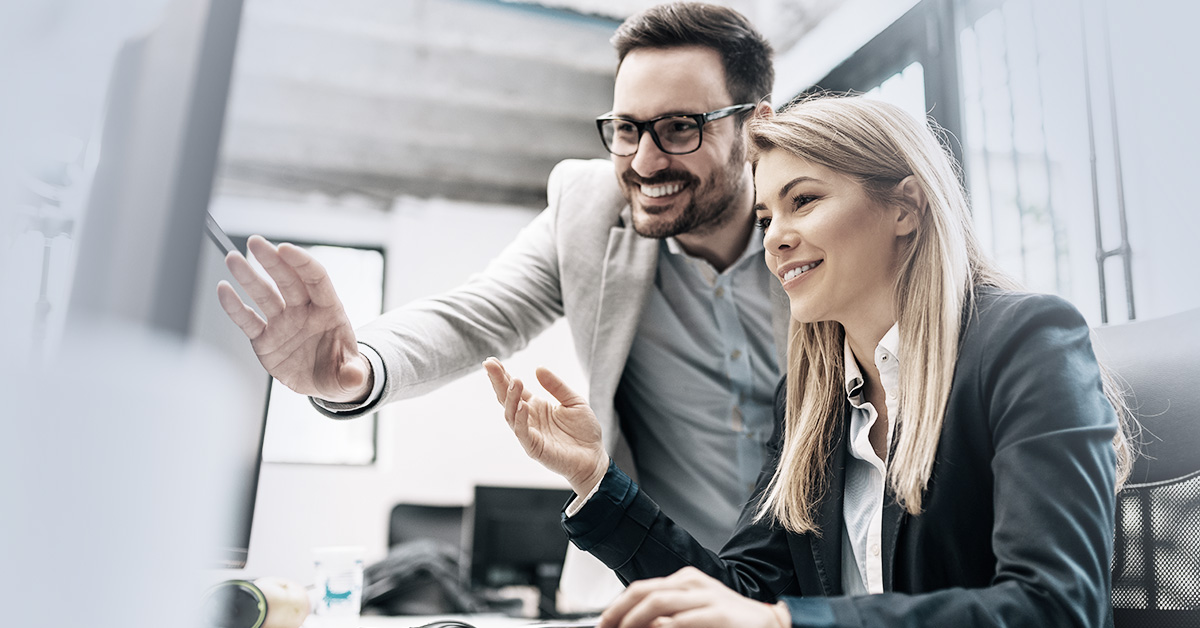 Two colleagues at a work station happy about using SheerID and Salesforce Commerce Cloud to boost B2C customer acquisition.