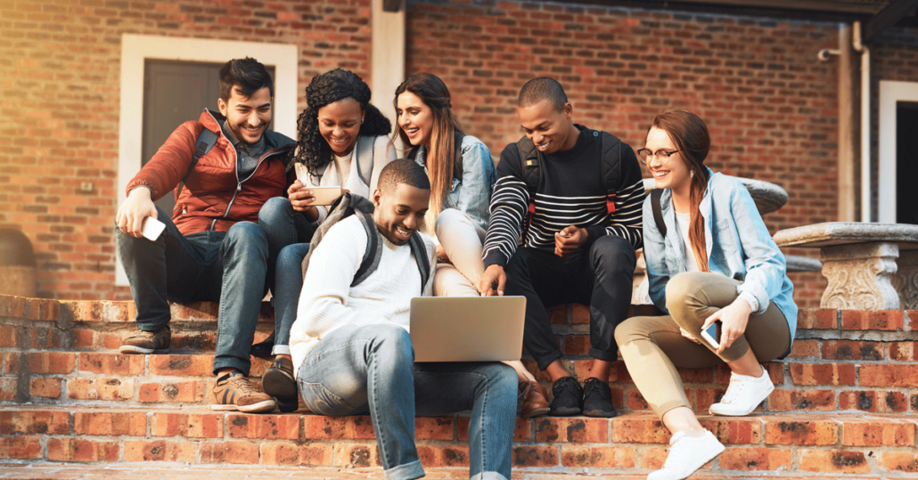 A group of Gen Zers gathered around a laptop to redeem a student discount using worldwide student verification.