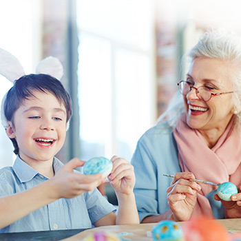 A grandparent and grandchild painting Easter eggs.