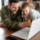 A military man in front of a laptop with his son, smiling about the personalized offer he just received.