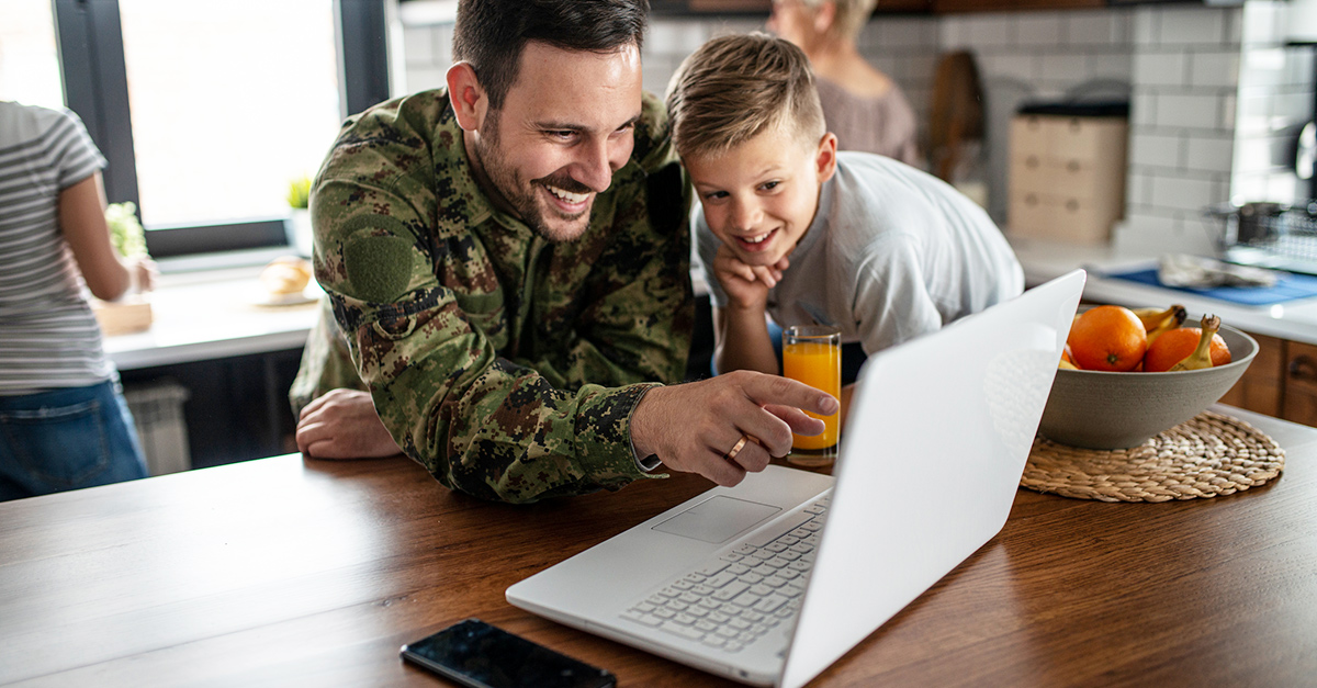 A military man in front of a laptop with his son, smiling about the personalized offer he just received.
