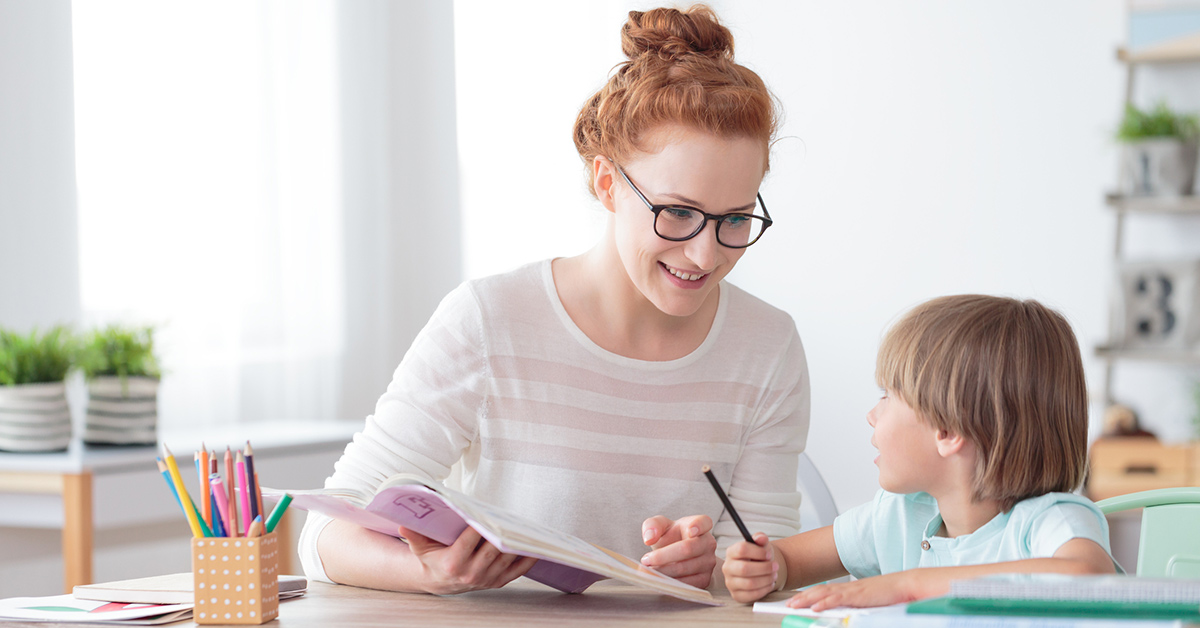 A smiling female teacher helps a young student using school supplies she bought with a personalized offer.