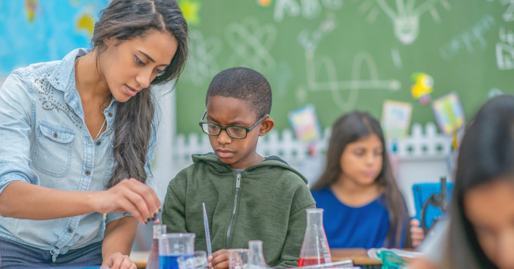 A teacher helping a student with a science experiment.