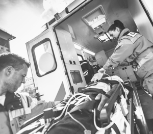 Two EMTs load a patient on a gurney into an ambulance.