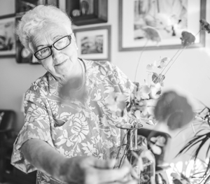 An elderly woman arranging flowers in her living room.