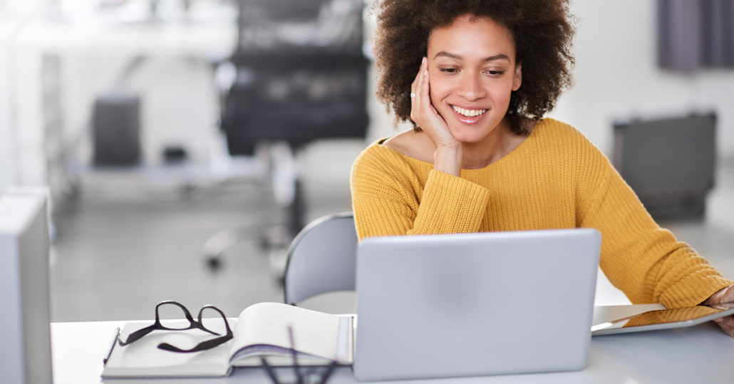 A woman in front of her laptop, happy that she qualified for a corporate discount through employment verification.