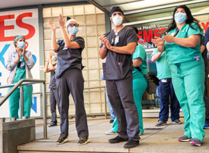 Medical workers stand outside a hospital clapping