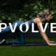 Woman doing yoga behind PVOLVE logo