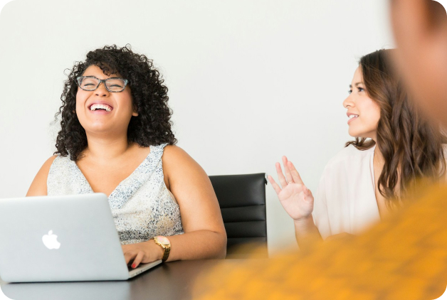 Woman smiling on laptop in meeting.