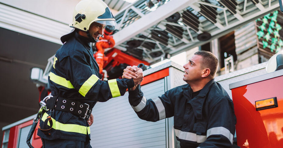 Two firefighters clasp hands in a gesture of camaraderie.