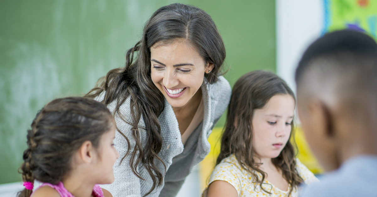 Teacher smiling in elementary school classroom.