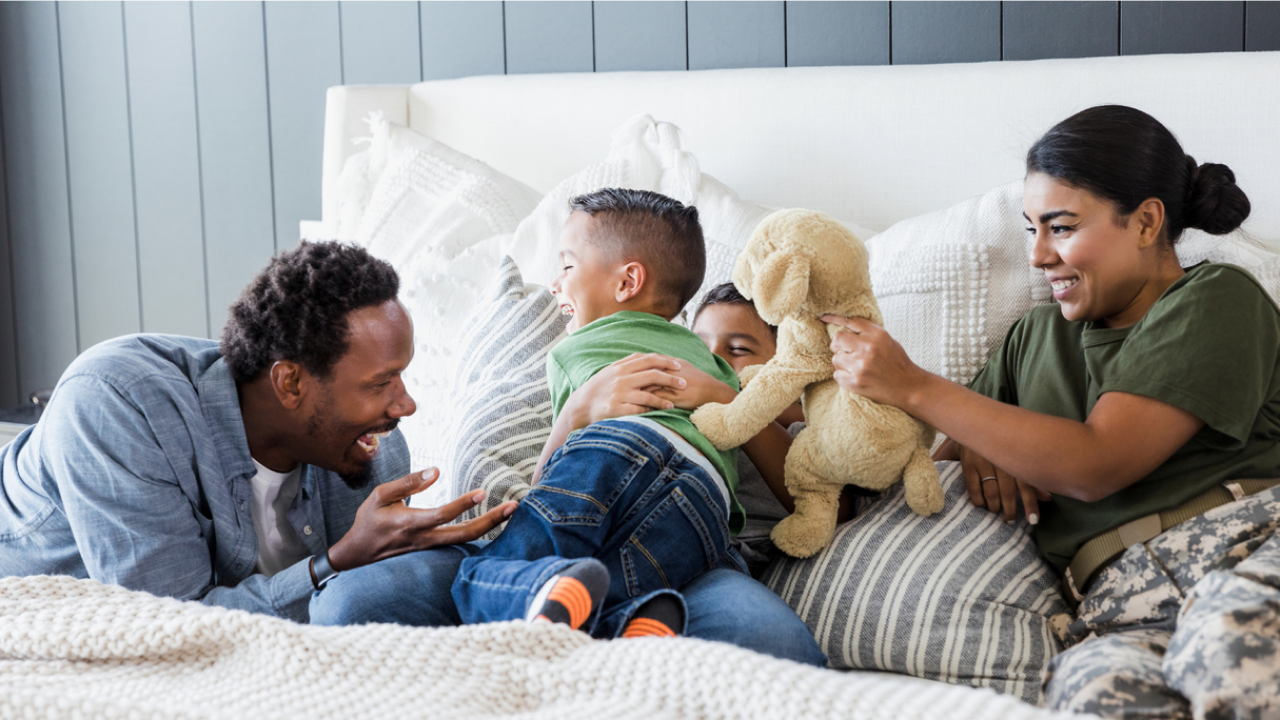 Smiling military family sharing a laugh while sitting in bed.
