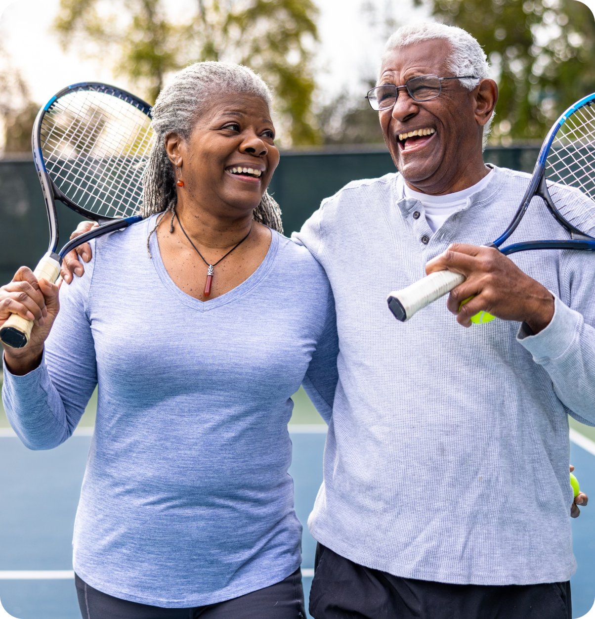 Two older adults holding tennis rackets.