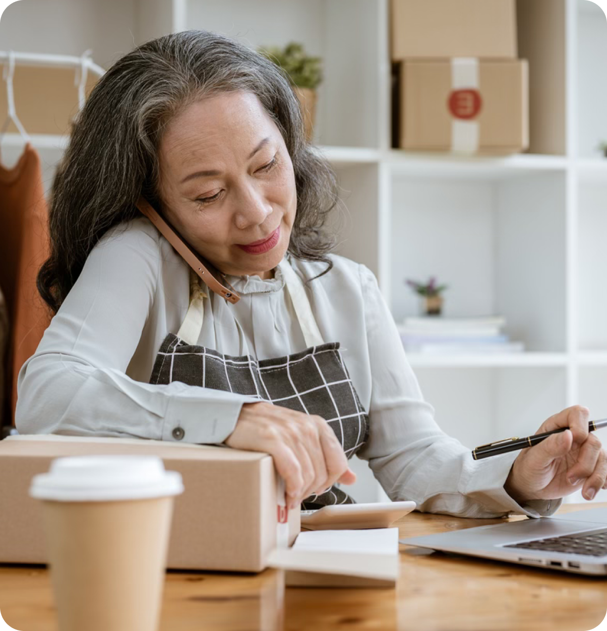 Older adults uses calculator while on phone.