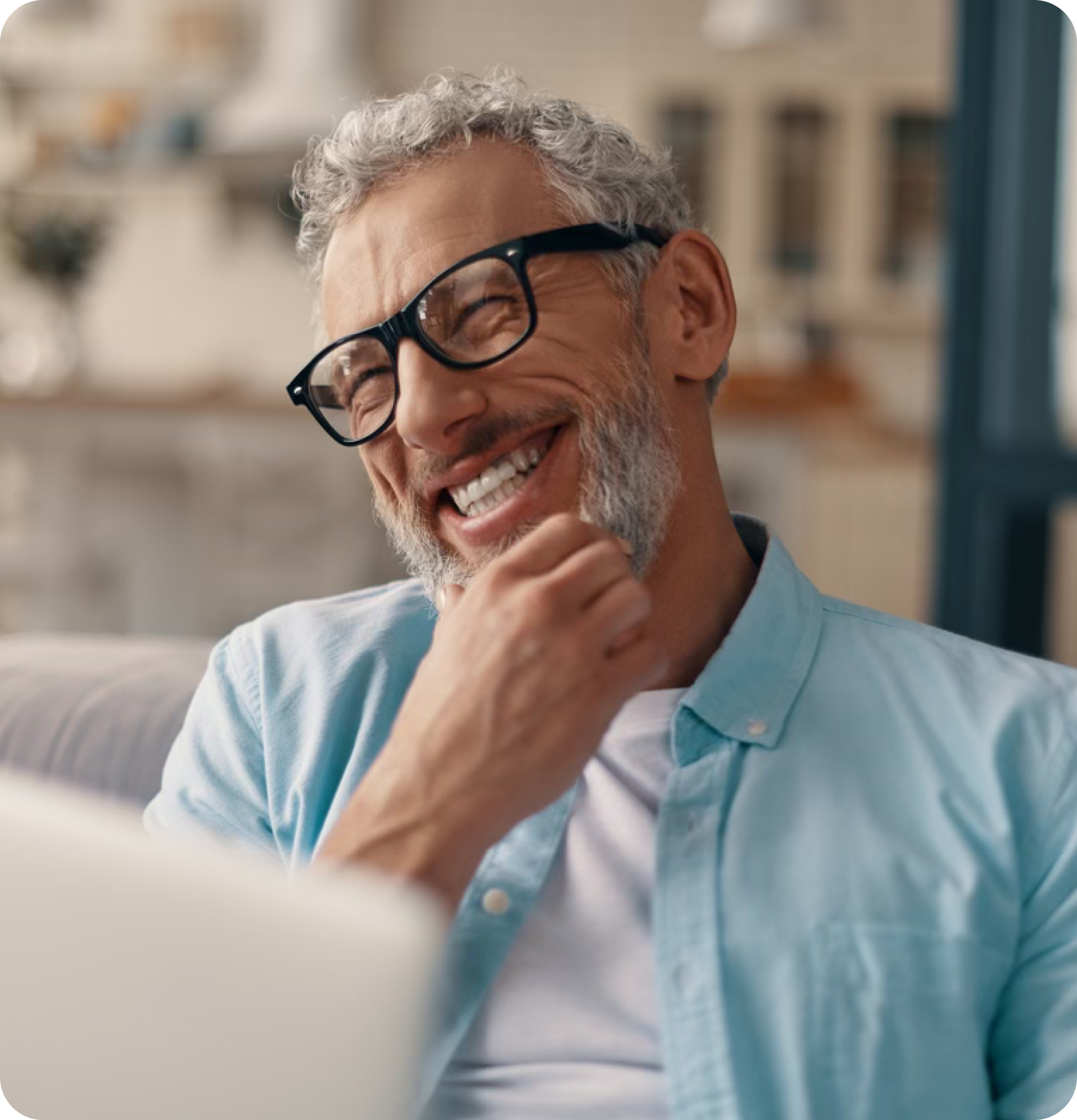 Older man smiles at laptop.