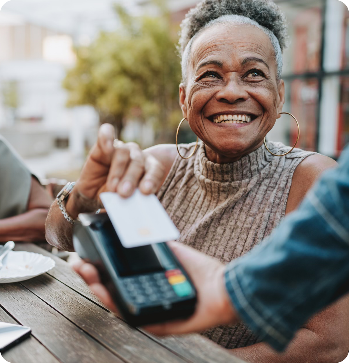 Older adult taps to pay bill at restaurant.