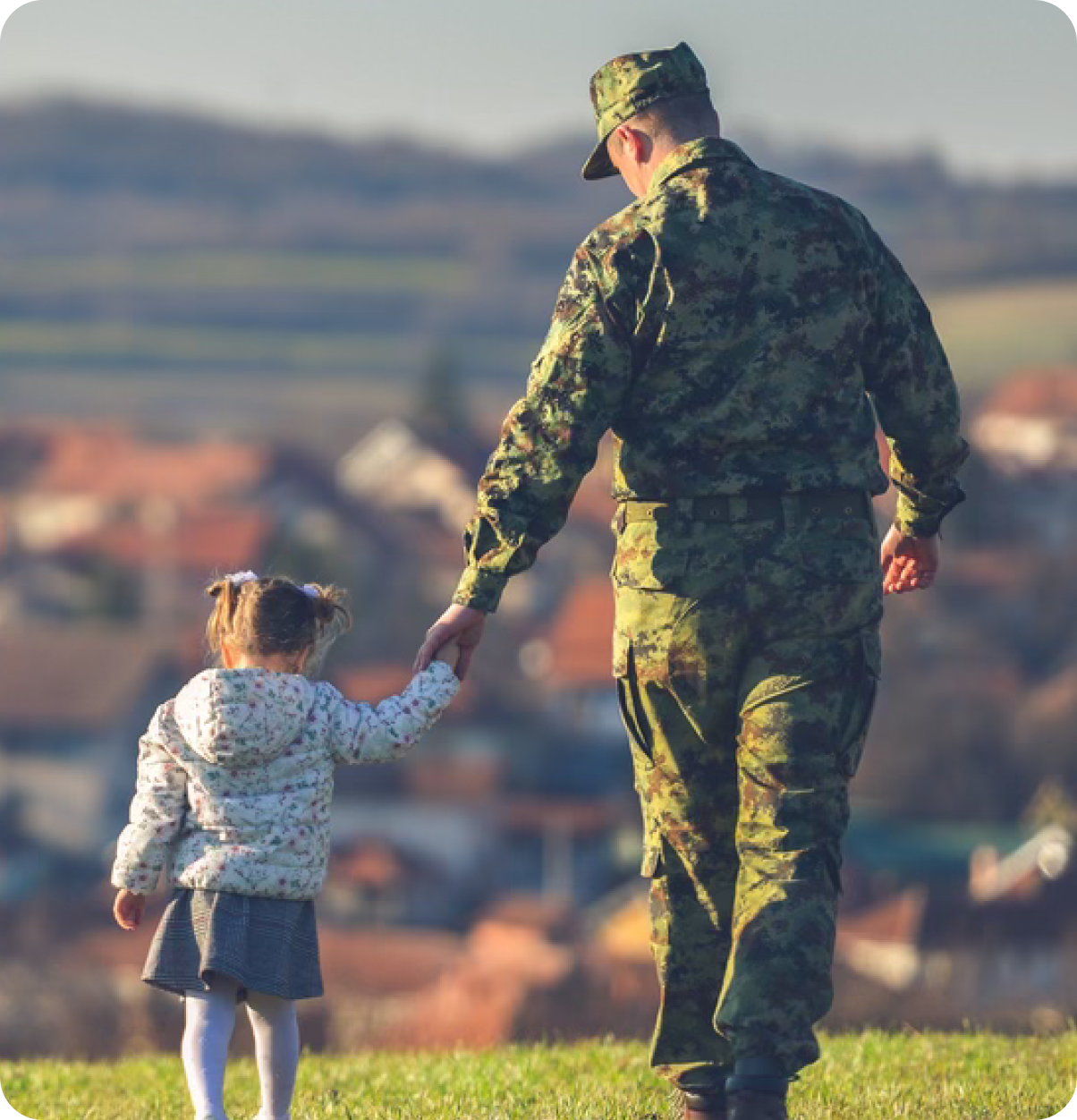 Military father holds hand of child.