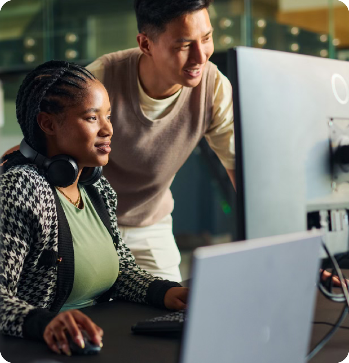 Woman and man look at monitors.