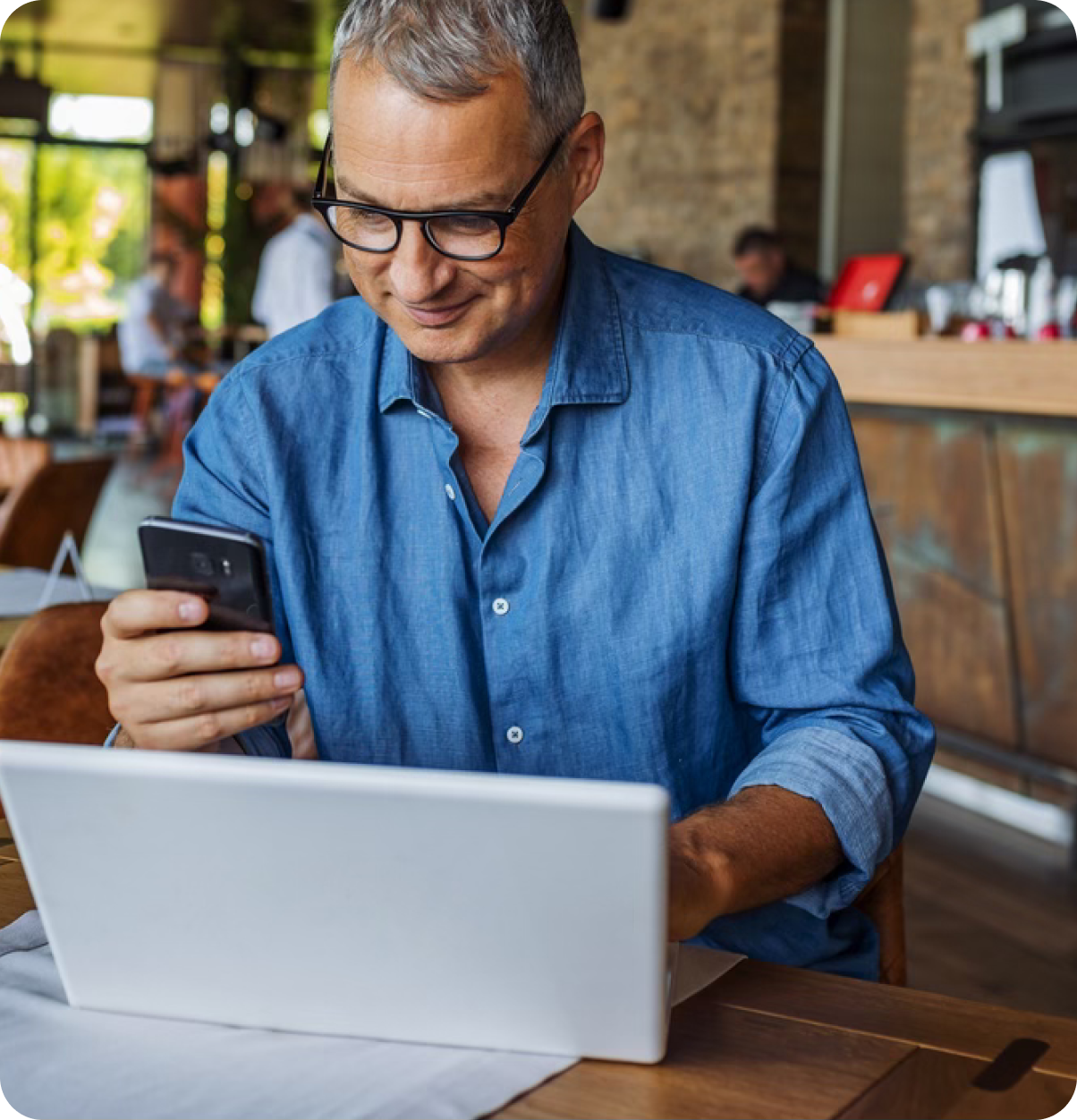 Older adult uses phone and laptop.