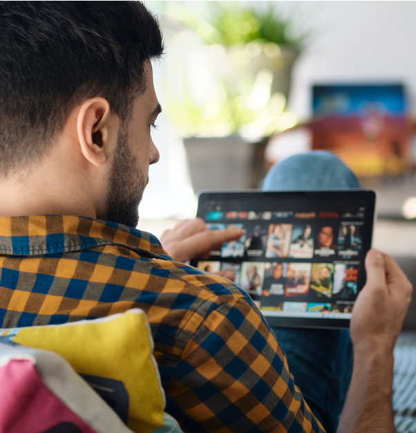 Man scrolls tablet on Peacock screen.