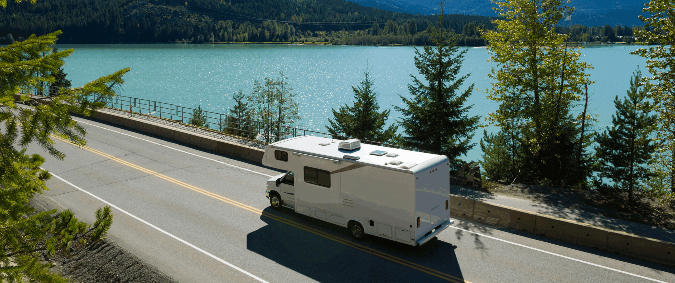 RV travels on scenic lake road.