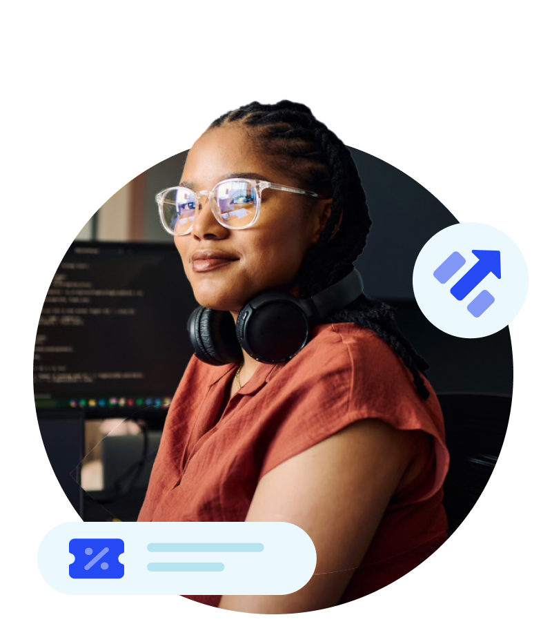 Woman wearing glasses in front of computer monitors with code.