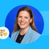 Blog graphic featuring a smiling woman, Lara, wearing a light blue blazer in a circular portrait. The blue background includes a binary code heart icon and abstract dashed lines.